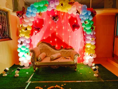 Colorful balloon arch and fairy lights birthday party stage decoration with royal sofa in Kolkata event hall.