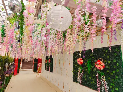 Beautiful floral hanging decorations with pink, white, and purple flowers, green foliage wall, and white paper lanterns in Kolkata event venue.