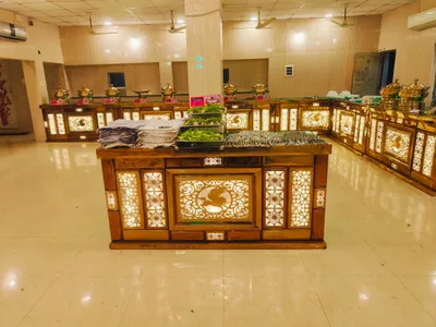 Illuminated buffet counters with stainless steel serving dishes and fresh salad setup in banquet hall for wedding catering in Behala, Kolkata.