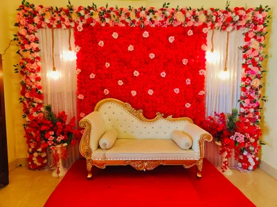 Luxurious wedding stage decoration with red and pink flower backdrop and royal sofa in Kolkata event hall.