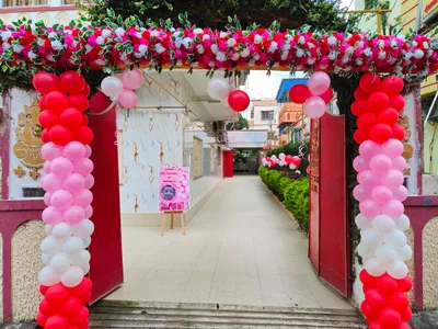 Entrance of banquet hall in Behala, Kolkata decorated with pink and white flower garland and balloon pillars for rice ceremony event