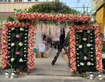 Grand wedding venue entrance in Behala, Kolkata decorated with vibrant floral arch, greenery panels, and cascading flowers for reception event
