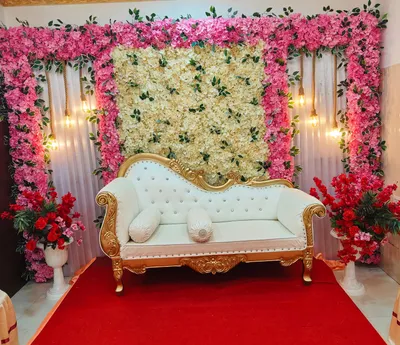 Elegant wedding stage with gold vintage sofa, pink and cream floral backdrop, and decorative lighting in banquet hall, Behala, Kolkata