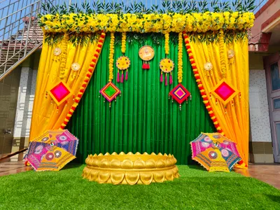 Bright yellow and green Haldi ceremony stage decoration with marigold flowers, colorful umbrellas, and traditional Indian hanging decor in Kolkata.