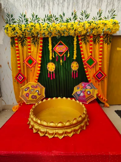 Traditional haldi ceremony setup with yellow floral decorations, colorful umbrellas, and ceremonial stage in biye bari, Behala, Kolkata