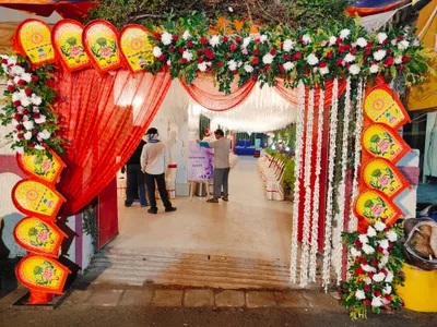 Traditional biye bari entrance decorated with red drapes, floral garlands, and colorful hand fans for Bengali wedding in Behala, Kolkata