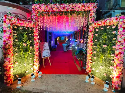 Grand wedding entrance decorated with pink floral arch, greenery panels, and LED lighting at biye bari in Behala, Kolkata