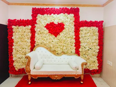 Elegant white and gold sofa with floral backdrop of red and white flowers forming heart shape for wedding decoration at Marriage Hall in Behala, Kolkata
