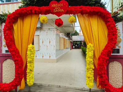 Wedding entrance arch decorated with red and yellow floral garlands and golden drapes at Marriage Hall in Behala, Kolkata