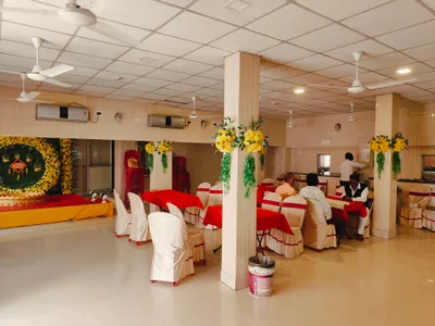 Banquet hall in Behala, Kolkata with red and white decorated seating and floral arrangements, featuring catering staff preparing for event