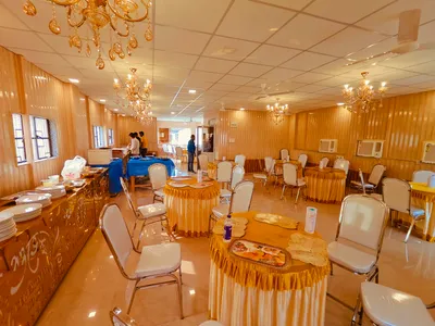 Banquet hall with golden chandeliers, round tables with yellow skirts, and buffet setup for wedding catering in Behala, Kolkata