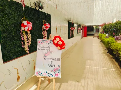 Floral welcome board for Shreyasee and Amit wedding with hanging flower decorations and green wall entrance decor in Kolkata.