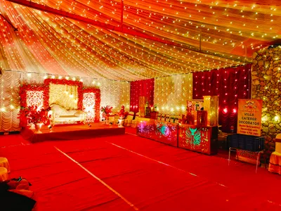 Luxurious wedding stage decoration with white floral backdrop, red flowers, and elegant sofa under fairy light canopy in Kolkata event hall.
