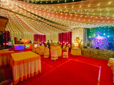 Wedding event hall in Kolkata decorated with fairy lights, draped ceiling, red carpet, buffet counters, and Ganesh idol stage decor.